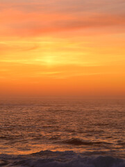 Obraz premium Sunset over the ocean. The light from the setting sun casts beautiful orange and golden hues onto the altostratus-type clouds.