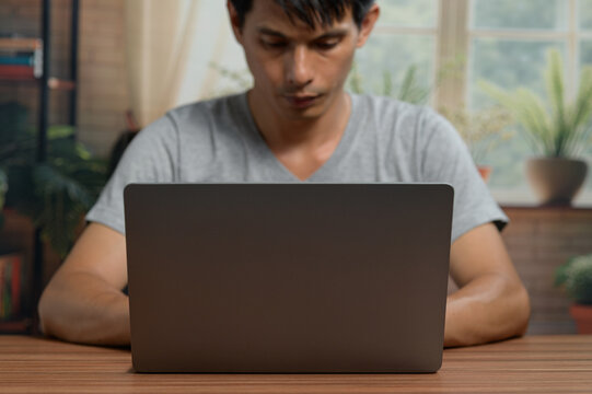 Young Man Concentrating on Laptop in Indoor Space with Natural Light