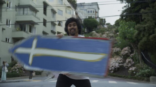 Man Spinning Painted Boards on Urban Street In San Francisco With Winding Hill