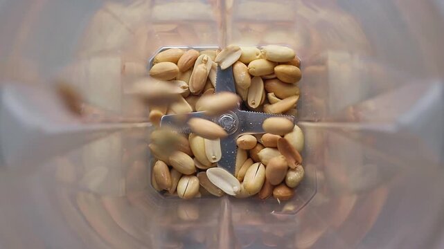 Peanuts falling into blender to make homemade peanut butter
