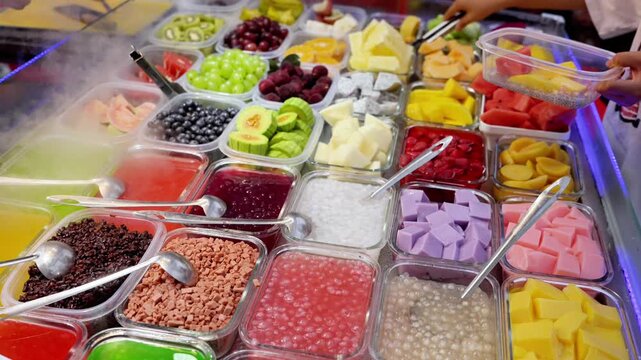 A variety of fresh fruit, jelly and toppings arranged in plastic containers for self-serve dessert or frozen yogurt bar.