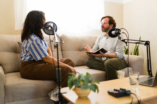 Podcaster interviewing guest in home studio, recording audio content for online broadcast and media creation