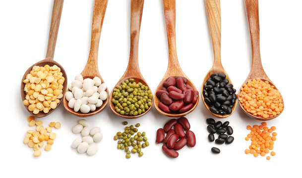 Different types of legumes in wooden spoons isolated on white