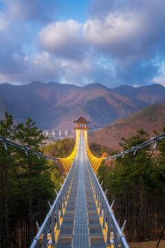 Bongmyeongsan suspension bridge with traditional Korean pavilion pavilion leading to beautiful autumn mountains backdrop, famous tourist landmark and hiking destination in Mungyeong, South Korea.