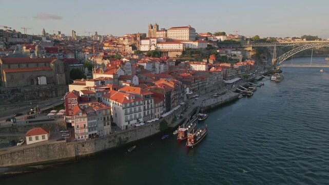 Aerial view of Ribeira do Porto featuring historic colorful buildings along the Douro river, traditional rabelo boats, and the Dom Luis I Bridge in Porto, Porto, Portugal.
