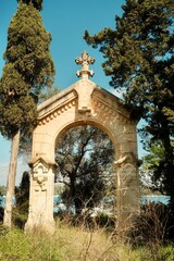 Fototapeta premium Historic stone archway surrounded by Mediterranean trees and coastal landscape
