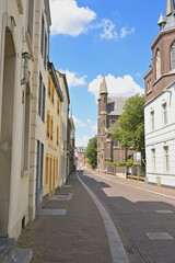 Fototapeta premium Sittard historic street view in old town with traditional Dutch architecture, cobblestone pavement and church towers under blue sky, Netherlands