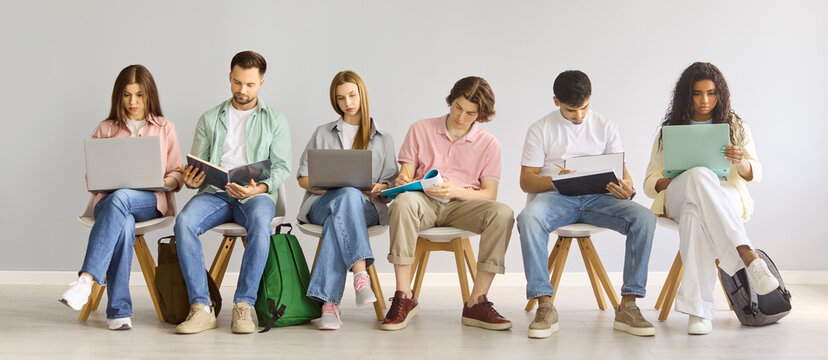 Students studying and learning with laptops in classroom. A diverse group sits in a row using laptops notebooks and tablets for university study. Strong concept of education and teamwork.