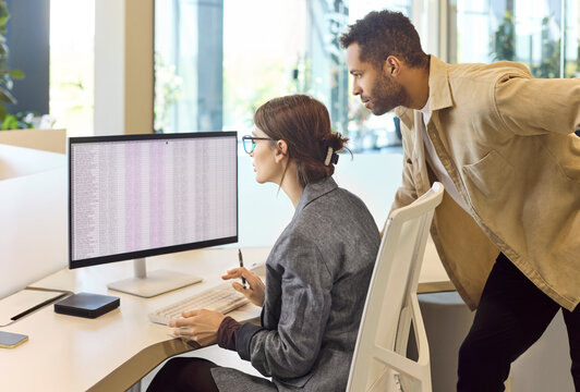 Colleagues analysts at office computer monitor reviewing spreadsheet data. Focused specialists audit figures and prepare a clear report. Teamwork and collaboration support financial accuracy.