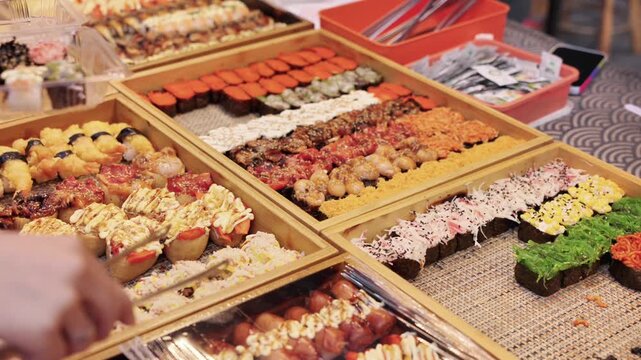 A wooden platter displays a diverse assortment of freshly prepared sushi with various fish and seafood toppings, arranged neatly for serving.