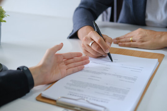 Close up of business people reviewing a contract agreement and preparing to sign legal documents.