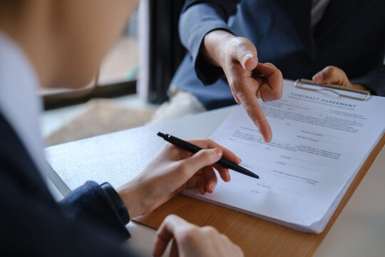 Close up of business people reviewing a contract agreement and preparing to sign legal documents.