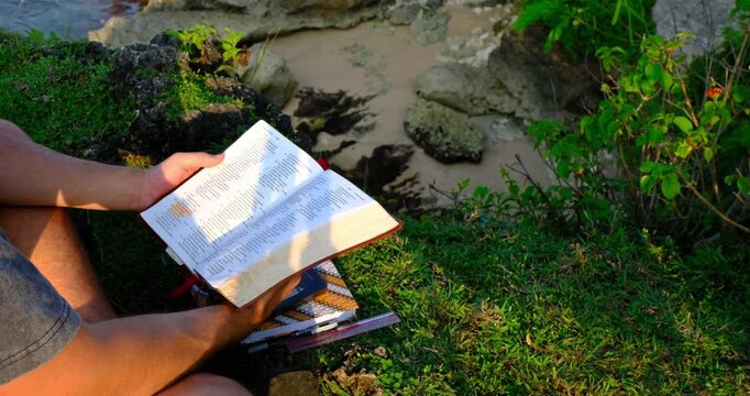 Man Reading Scripture Outdoors on Scenic Cliff in Bali