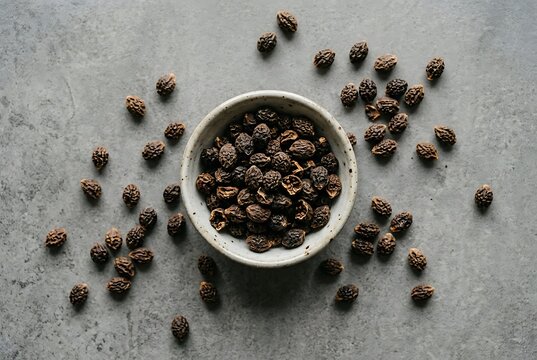 Dried haritaki fruit in a ceramic bowl on grey stone background