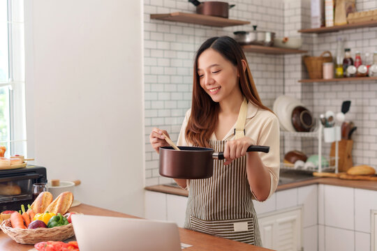 Woman cooking meal following online tutorial on laptop