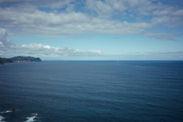 Fototapeta premium Panoramic view of the Atlantic Ocean with dramatic clouds, distant coastline and deep blue water on the northern coast of Spain.