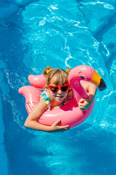 A child swims in a pool surrounded by flamingos. Selective focus.