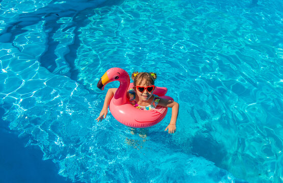 A child swims in a pool surrounded by flamingos. Selective focus.