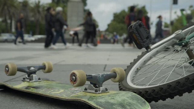 Skateboard and Bicycle Wheel Close-Up With Pedestrians Walking In Background