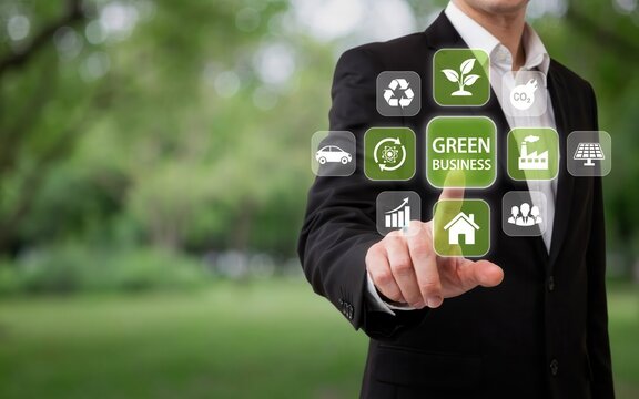 Businessman touching a virtual screen with green business icons