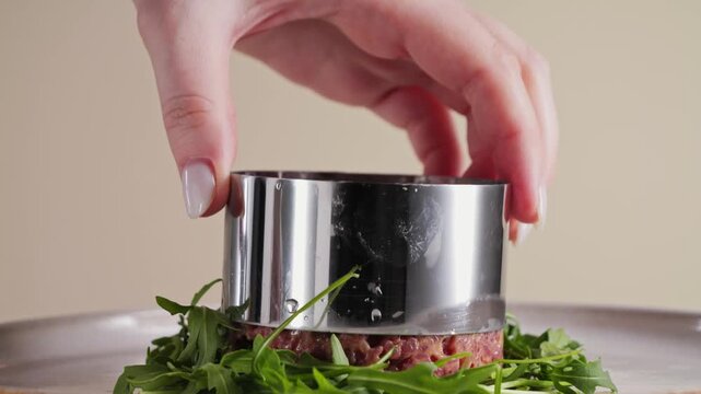 Arranges the diced raw beef using a metal ring mold on a plate, preparing an elegant dish steak tartare. High quality 4k footage