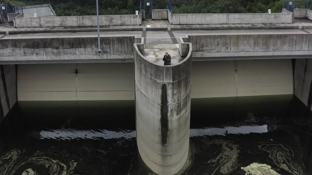 Aerial view of a photographer standing on the concrete structure of the Albufeira da Barragem de Couto de Esteves dam in Sever do Vouga, Aveiro District, Portugal.