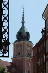 Obraz premium Historic clock tower of Royal Castle stands under a clear blue sky. Ancient landmark building rises between city streets in old town of Warsaw Poland, creating a scenic travel destination.