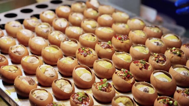 Baked egg shells served as edible cups, filled with assorted savory and sweet fillings arranged neatly on a baking tray for preparation.