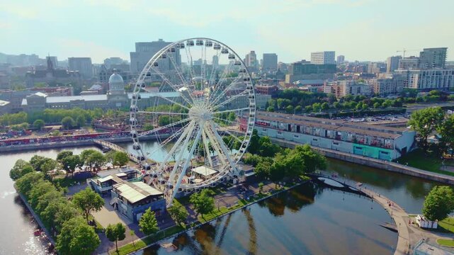 Montreal, Canada - June 29 2026: A stunning 4K aerial sweep over Montreal's historic Old Port, capturing the magnificent, modern silhouette of La Grande Roue spinning gracefully beside the sparkling S
