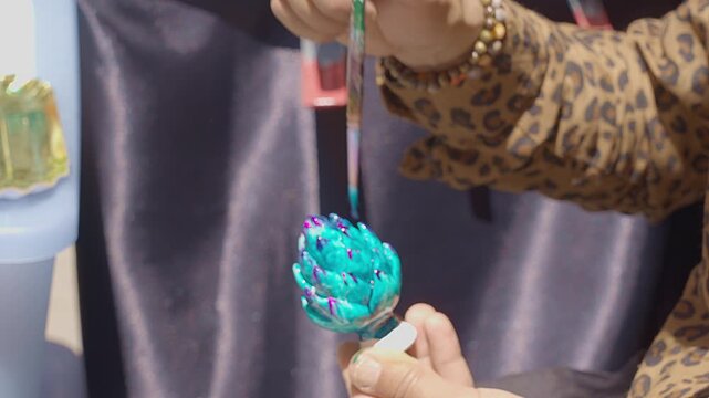the skilled hands of a craftsman painting a ceramic piece depicting the traditional Sicilian pine cone, a symbol of good luck