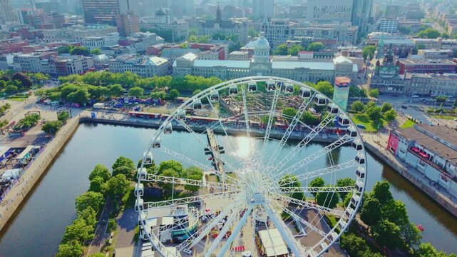 Montreal, Canada - June 29 2026: A stunning 4K aerial sweep over Montreal's historic Old Port, capturing the magnificent, modern silhouette of La Grande Roue spinning gracefully beside the sparkling S