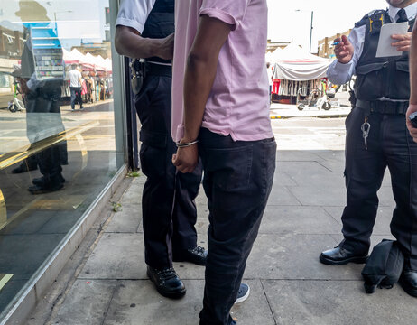A person suspected of a crime being arrested by police officers on the street.