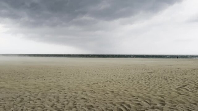 A sudden sandstorm hits a beach. Powerful wind gusts lifting sand across the shore as severe summer weather and storm clouds approach after a heatwave. Grado, Italy - July 1, 2026.