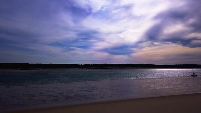 Calm coastal beach with reflective water and dramatic evening sky