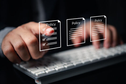 Businessman reviewing virtual policy documents and digital compliance rules floating over computer keyboard. Concept of corporate governance, legal regulations, and electronic terms agreement.