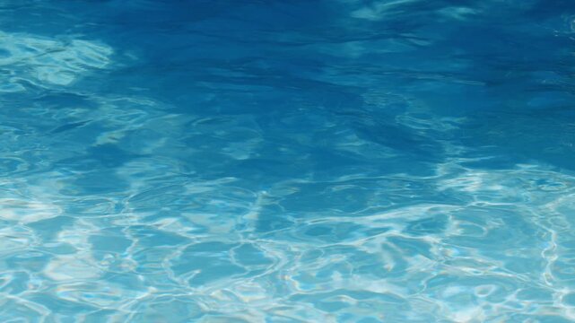 Ripples on the water of the pool, transparent, sparkling, inviting surface of the water in motion, view from above. slow motion and looped video.