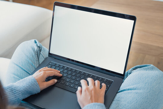Person working remotely using a laptop with a blank screen on their lap, typing on the keyboard, showcasing modern technology and connectivity