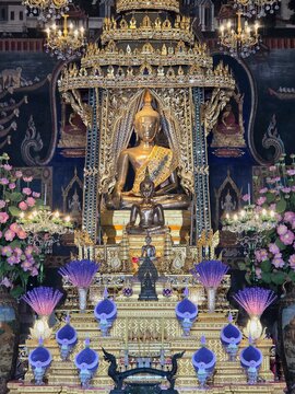 Phra Serm, a sacred glowing golden Buddha statue enshrined on an elaborately decorated base inside Wat Pathum Wanaram Ratchaworawihan temple, Bangkok, Thailand.