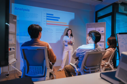A young businesswoman gestures confidently while presenting a financial analysis slide with growth charts and plan comparisons, illustrating a professional data presentation session