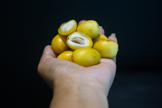A handful of fresh ripe yellow date palm fruits on a dark background.