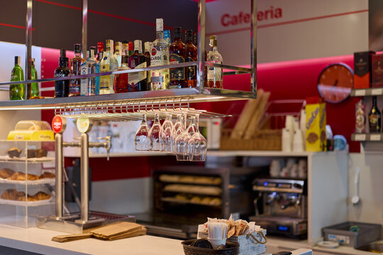 Coma-ruga, Spain - June 3, 2026: An empty interior bar counter zone with hanging clean glasses and bottles inside a local cafeteria on the Mediterranean coast of Catalonia.