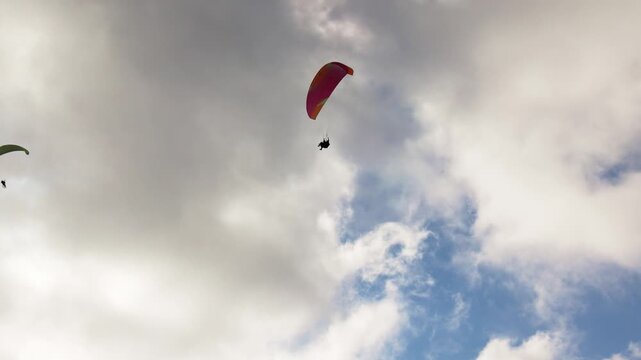 People try paragliding flying with parachutes against clouds