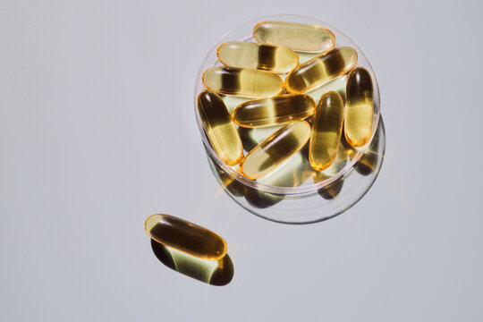 Yellow softgel capsules in clear dish providing essential dietary supplements