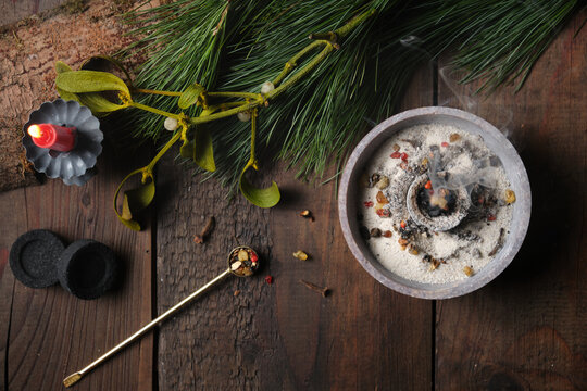 Frankincense, resins and dried herbs burning on glowing charcoal with dark background, copy space