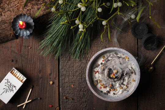 Frankincense, resins and dried herbs burning on glowing charcoal with dark background