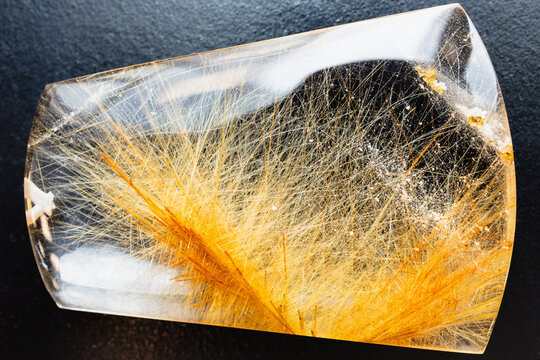 clear quartz stone with rutile crystals on black