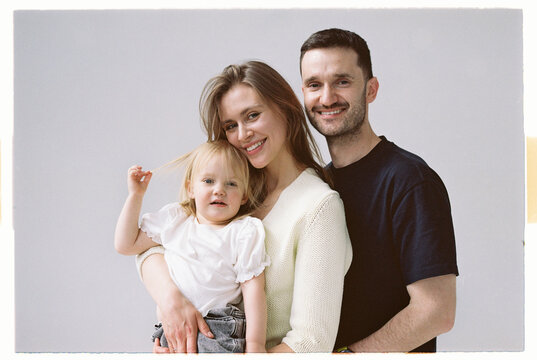 Family poses for a photo in a studio with soft background