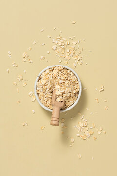 Overhead view of rolled oats in a white bowl with a wooden scoop