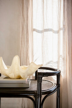 Vignette of shell decor on a trolley with linen curtain behind
