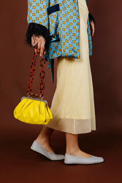 Womangwearing dress, jacket, and yellow clutch